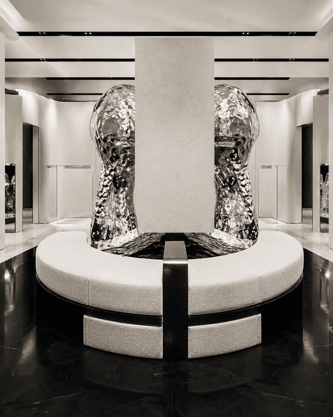 Abstract chrome installation behind a pale stone column in a minimalist gallery with a black marble floor